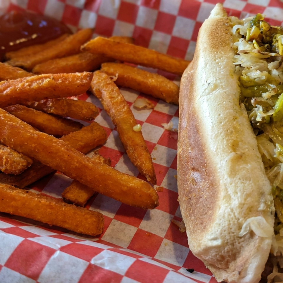 Burrito filled with rice, green peppers, and vegetables served with crispy fries on red-and-white checkered paper.