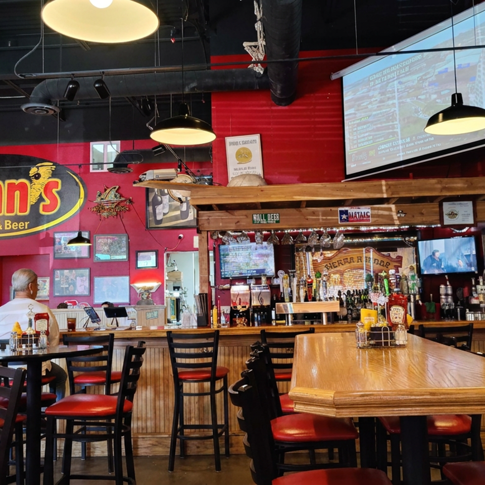 Spinns Burger & Beer dining room with red walls, bar, high tables, televisions, sports memorabilia, and seated patrons.